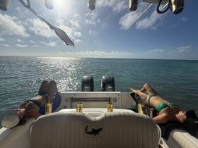 Two friends relax and sunbathe on the deck of a boat, enjoying the serene ocean views — a perfect day for unwinding on the water.