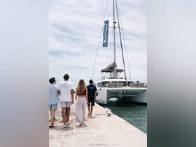 A group of friends walks towards a luxurious catamaran at the dock, ready for an exciting day on the water.