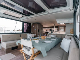 A beautifully designed interior of a boat featuring a spacious dining area with elegant seating and large windows, perfect for enjoying meals while cruising.