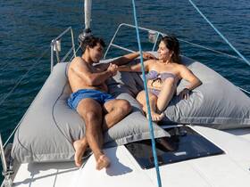 A couple enjoys a relaxing moment on a spacious boat, sunbathing and sharing smiles — perfect for a romantic getaway on the water.