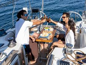 A lively group enjoys a toast with drinks and delicious snacks aboard a sailboat, capturing the essence of a perfect sailing adventure.