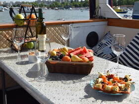 A beautifully arranged table featuring a selection of fresh fruits, wine, and snacks, perfect for enjoying a relaxing day on the water.