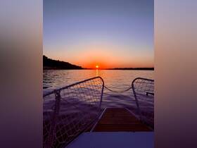 A serene sunset view from the bow of a boat, showcasing the tranquil waters and vibrant colors of the evening sky — perfect for peaceful evening cruises.