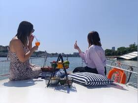 Two friends enjoy cocktails and snacks on a sunny day aboard a boat, perfect for relaxing outings and social gatherings on the water.