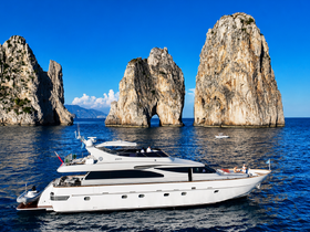 A stunning yacht glides through crystal-clear waters near iconic rock formations, showcasing the beauty of coastal scenery and luxury boating.