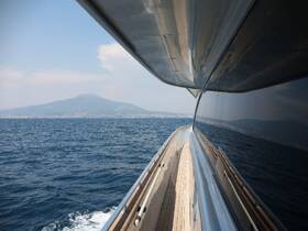 A stunning view of a yacht gliding through the water, showcasing the beautiful coastline and a distant mountain, perfect for luxury sailing experiences.