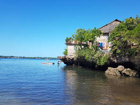 A scenic view of a coastal area featuring a stone house and a small boat, capturing the tranquil essence of waterfront living.