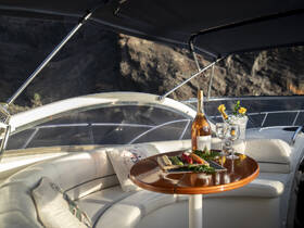 An elegant dining setup on a boat featuring a bottle of rosé, cocktails, and a gourmet platter, perfect for a luxurious day on the water.