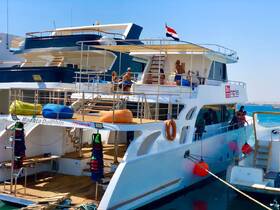 Guests enjoy a sunny day aboard the Marutta Dolphin, relaxing and sunbathing on the deck, showcasing the vibrant atmosphere of a boat trip.