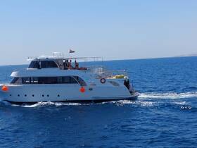 A luxurious yacht cruises through clear blue waters, showcasing a perfect day on the sea with guests enjoying the sun.