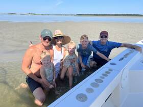 A joyful family enjoys a sandbar stop, playing in the shallow water and creating lasting memories together — perfect for summer adventures on the water.