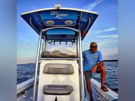 A man relaxes on the deck of a Bay Rider boat, enjoying the serene ocean view at sunset — a perfect moment for boating enthusiasts.
