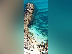 An aerial view of a rocky shoreline with clear turquoise waters, showcasing the natural beauty of the coastal environment.