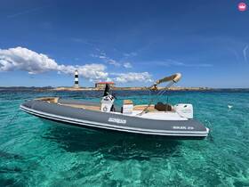 A sleek Salpa Soleil 20 speedboat anchored in crystal-clear waters, showcasing its elegant design against a picturesque lighthouse backdrop.