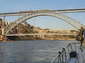 A scenic view of a boat navigating under a stunning bridge, showcasing the beautiful landscape along the river. Perfect for capturing memorable moments during a boat tour.