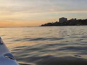 A serene sunset view from a boat, showcasing calm waters and a distant shoreline — perfect for peaceful evening cruises.