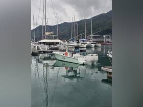 A sleek center console boat docked in a marina, surrounded by various sailboats and stunning mountain scenery, perfect for exploring coastal waters.