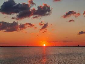 A stunning sunset over calm waters, showcasing vibrant colors and a serene atmosphere — perfect for evening boat cruises.