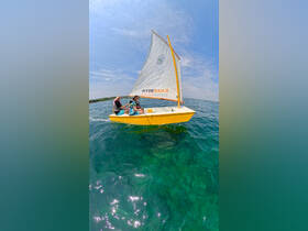 Two children enjoy sailing on a vibrant yellow sailboat, creating unforgettable memories on the water — perfect for family adventures.