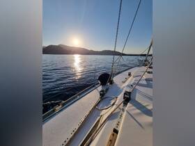 A serene view from the deck of a sailboat at sunset, showcasing the tranquil waters and distant hills — perfect for peaceful sailing experiences.