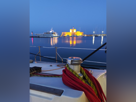 A serene night view of a harbor featuring a beautifully illuminated castle and luxurious yachts, perfect for capturing the essence of coastal adventures.