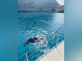 A person dives into the crystal-clear waters from the side of a boat, capturing the thrill of summer adventures on the water.