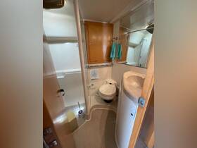 A clean and functional bathroom inside a boat, featuring a toilet, sink, and shower area, ideal for comfortable cruising experiences.