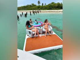 A lively group enjoys a fun day on a floating mat in crystal-clear waters, perfect for relaxation and socializing under the sun.