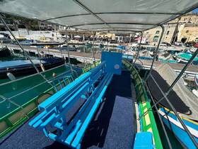 Interior view of a boat featuring bright blue seating and a spacious layout, perfect for comfortable cruising or group outings.