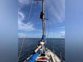 A fun moment aboard a sailboat with a child climbing the mast and an adult relaxing on the deck, showcasing the joy of sailing and ocean adventures.