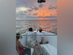 A group of friends enjoys a stunning sunset from the deck of a boat, creating a perfect backdrop for memorable moments on the water.