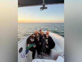 A fun group of friends celebrates on a boat at sunset, wearing festive hats and enjoying drinks — perfect for memorable boat parties.