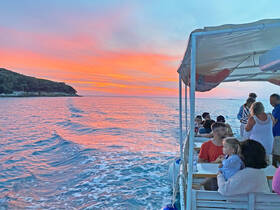 A vibrant sunset casts a beautiful glow over a group enjoying a boat ride, creating a perfect backdrop for family moments and celebrations on the water.