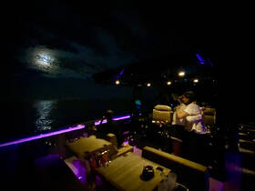 A couple shares a romantic moment under the moonlight on a luxury boat, creating the perfect atmosphere for a night cruise.