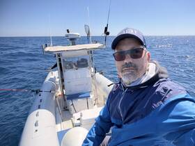 A man enjoys a day of fishing on a boat in the open ocean, showcasing the thrill of angling in a serene marine environment.