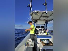 An angler prepares to cast a line while fishing on a boat in the open ocean, showcasing the thrill of deep-sea fishing adventures.