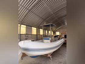 A well-maintained inflatable boat is showcased inside a storage facility, highlighting its console and helm area — perfect for water adventures.