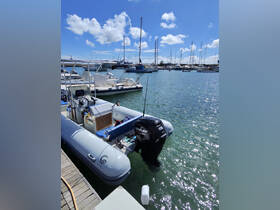 A sleek speedboat docked at a marina, showcasing its design against a backdrop of other vessels and a clear blue sky.