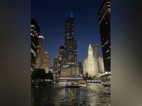 A scenic view of Chicago's skyline at night, featuring a boat cruising along the river, perfect for evening city tours and sightseeing.