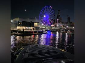 A stunning night view from the bow of a boat, showcasing a vibrant city skyline and a colorful Ferris wheel, perfect for evening cruises and urban adventures.