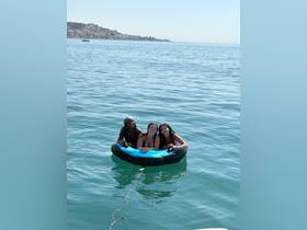 Three friends enjoy a fun day on the water, relaxing on a floating tube in the beautiful sea — perfect for summer adventures and beach outings.