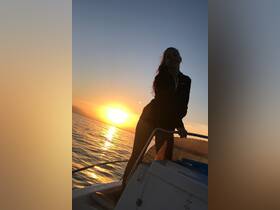 A young girl enjoys a beautiful sunset aboard a boat, capturing the essence of joyful moments on the water.