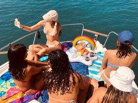 A group of friends enjoys a sunny day on the boat, capturing memories while relaxing with snacks and drinks — the perfect setting for a fun day on the water.