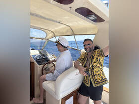 Two friends enjoy a sunny day on the water, with one at the helm and the other capturing the moment — perfect for memorable boating adventures.