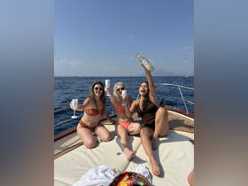 Three friends celebrate on the deck of a yacht, raising their glasses in a toast against a stunning ocean backdrop — perfect for unforgettable summer outings.