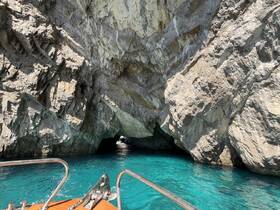 A stunning view of a boat navigating through a rocky cave, surrounded by crystal-clear turquoise waters — a perfect representation of coastal adventures.