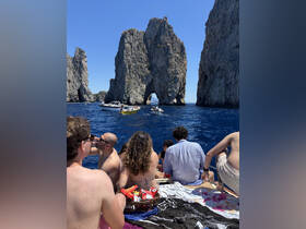 A lively group enjoys a day on the water, surrounded by stunning rock formations and sharing snacks — a perfect setting for a memorable boating adventure.