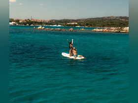 A couple enjoys paddleboarding in crystal-clear waters, celebrating their day on the water with joyful poses — perfect for summer adventures.
