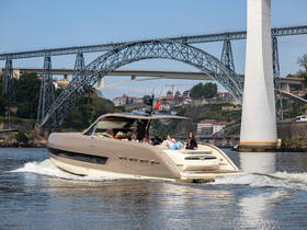 A stylish yacht cruises along the river with a group of guests enjoying the scenic view of a stunning bridge in the background — perfect for memorable outings on the water.