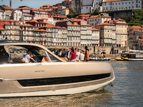 A lively group enjoys a day on the water aboard an Invictus boat, with the picturesque cityscape of Porto as a stunning backdrop.
